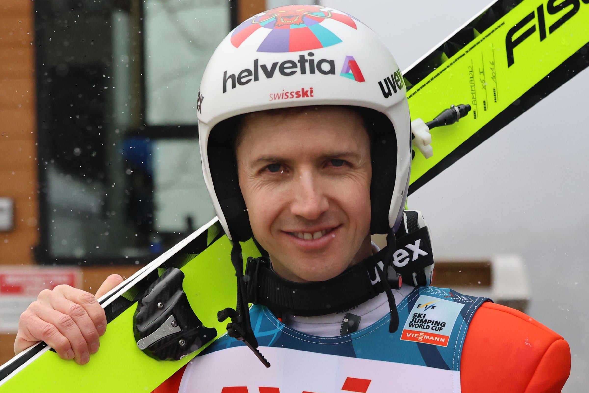 Skoczek narciarski Simon Ammann z nartami na ramieniu